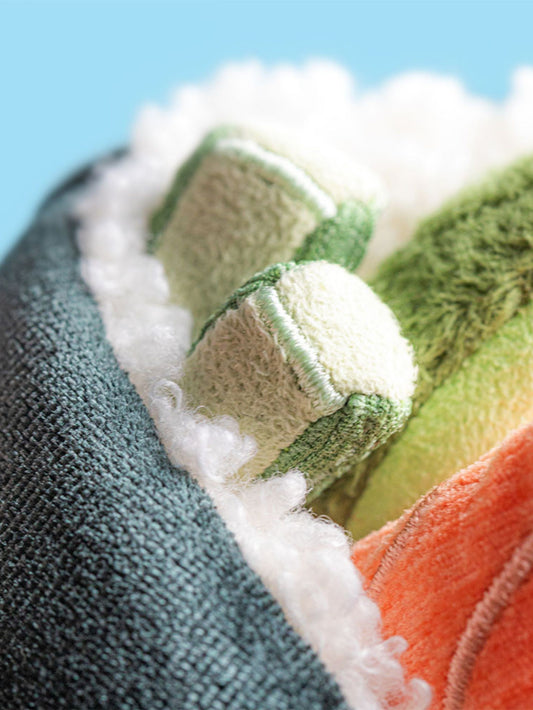 Close-up of a textured fabric with green, orange, and white colors against a blue background.