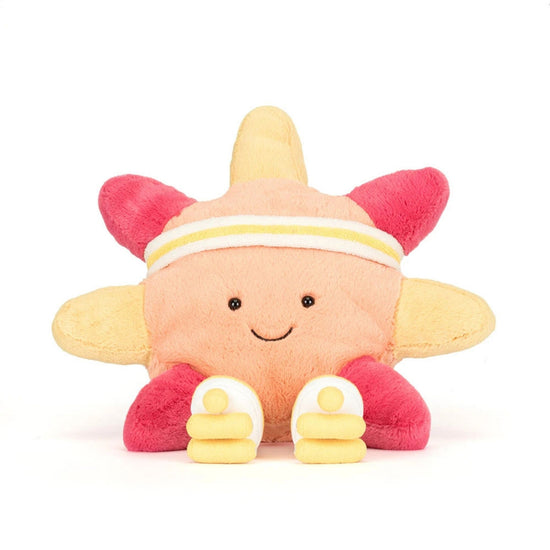 A plush toy shaped like a smiling sun or flower with a peach face, yellow petals, pink petals, and small white shoes, photographed on a clean white background.