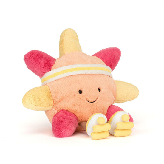 A plush toy character with a peach-colored body, pink ears and feet, yellow wings and hands, and a white and yellow headband, sitting against a plain white background.