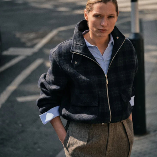 Person wearing a dark jacket and brown pants on a street.