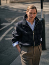 Person wearing a dark jacket and brown pants on a street.