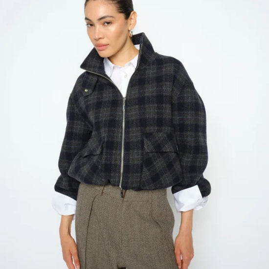 Woman wearing a plaid jacket and gray pants on a white background