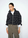 Woman wearing a plaid jacket and gray pants on a white background