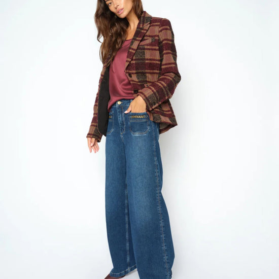 Woman wearing a plaid jacket, purple top, and blue jeans on a white background