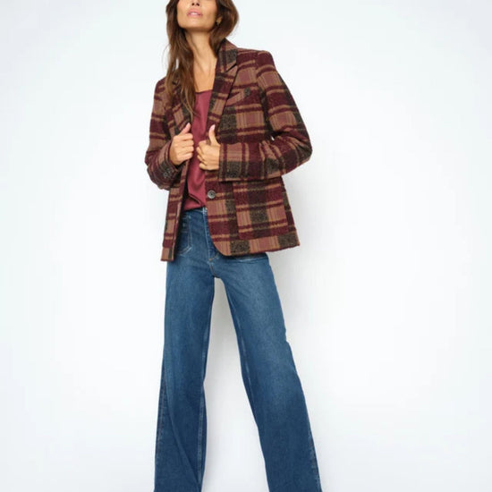 Woman wearing a plaid jacket, purple top, and blue jeans on a white background