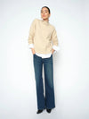 Woman wearing a beige sweater and blue jeans on a white background