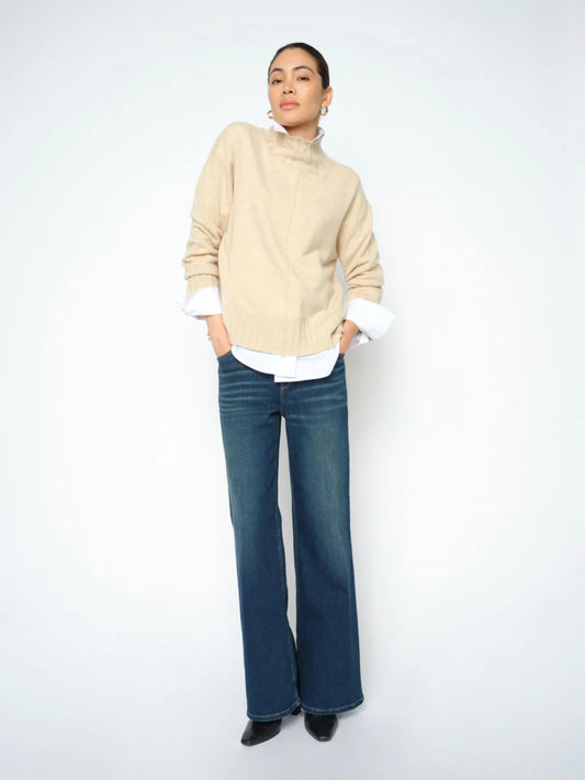 Woman wearing a beige sweater and blue jeans on a white background