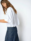 Person wearing a white shirt and blue jeans against a plain background