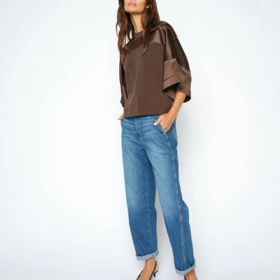 Woman wearing a brown top and blue jeans on a white background