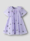 A light purple baby dress with a ruffled Peter Pan collar and scattered embroidered pineapples, shown against a neutral light gray background.