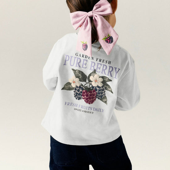 Person wearing a white sweatshirt with a berry graphic and text on a plain background