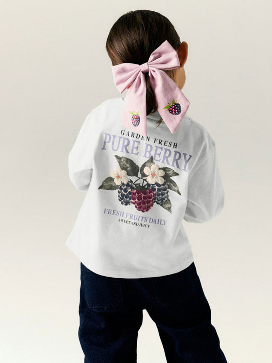 Person wearing a white sweatshirt with a berry graphic and text on a plain background