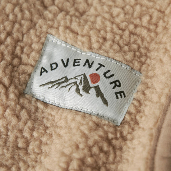 Close-up of a 'Adventure' label on a textured beige fabric surface