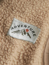 Close-up of a 'Adventure' label on a textured beige fabric surface