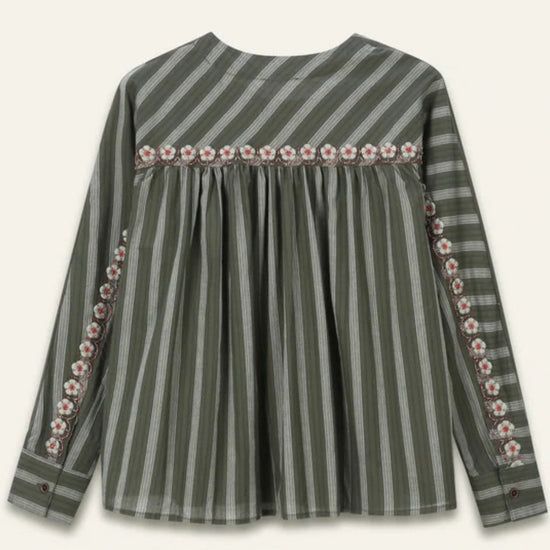 A long-sleeve striped top in olive green with a decorative floral border across the chest and along the sleeve cuffs, shown against a light cream background.