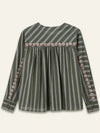 A long-sleeve striped top in olive green with a decorative floral border across the chest and along the sleeve cuffs, shown against a light cream background.