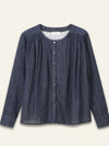 A dark blue chambray button-up blouse with a smocked neckline, long sleeves, and a relaxed fit, shown against a light cream background.