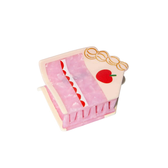 Pink cake-shaped hair clip with cherry detail on a white background