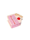 Pink cake-shaped hair clip with cherry detail on a white background