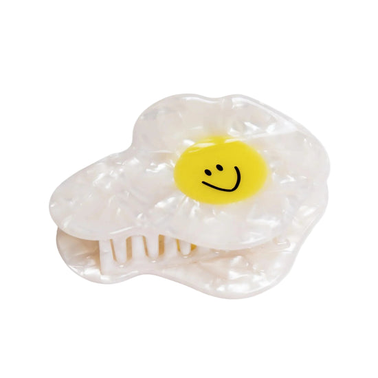 Clear plastic hair clip shaped like a fried egg with a smiley face on a white background