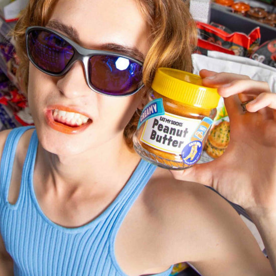 Person holding a jar of socks that look like peanut butter in a store setting