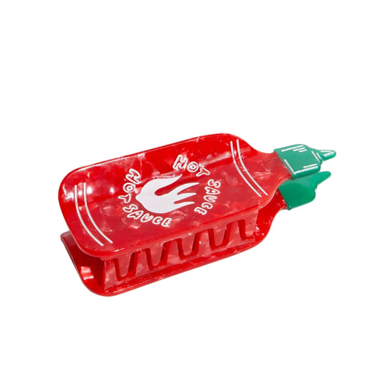 Red hot sauce bottle shaped hair clip on a white background