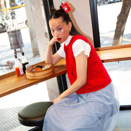 Woman sitting at a cafe counter with a red hot sauce shaped hair clip in hair.