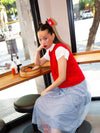 Woman sitting at a cafe counter with a red hot sauce shaped hair clip in hair.