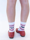White socks with red and black text worn with red shoes on a white background