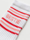 White sock with red and pink stripes and the word 'Bestie' on a white background