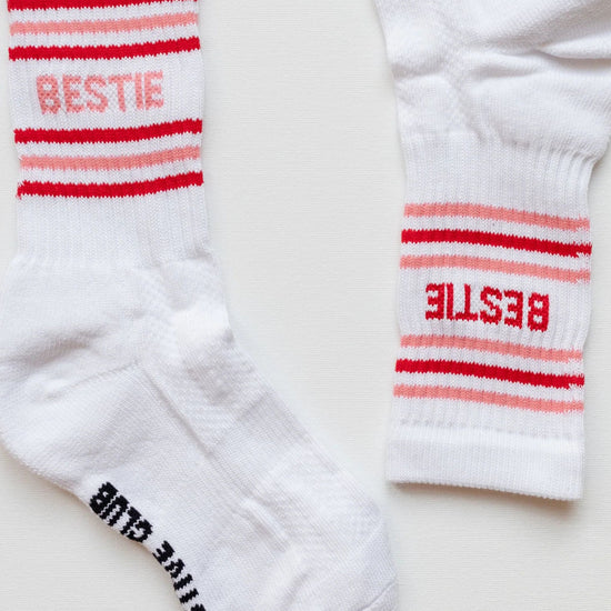 White socks with red and pink stripes and 'BESTIE' text on a light background