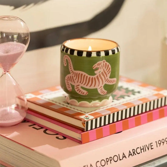 Paddywax black cedar and fig candle in a green container with a pink tiger design 