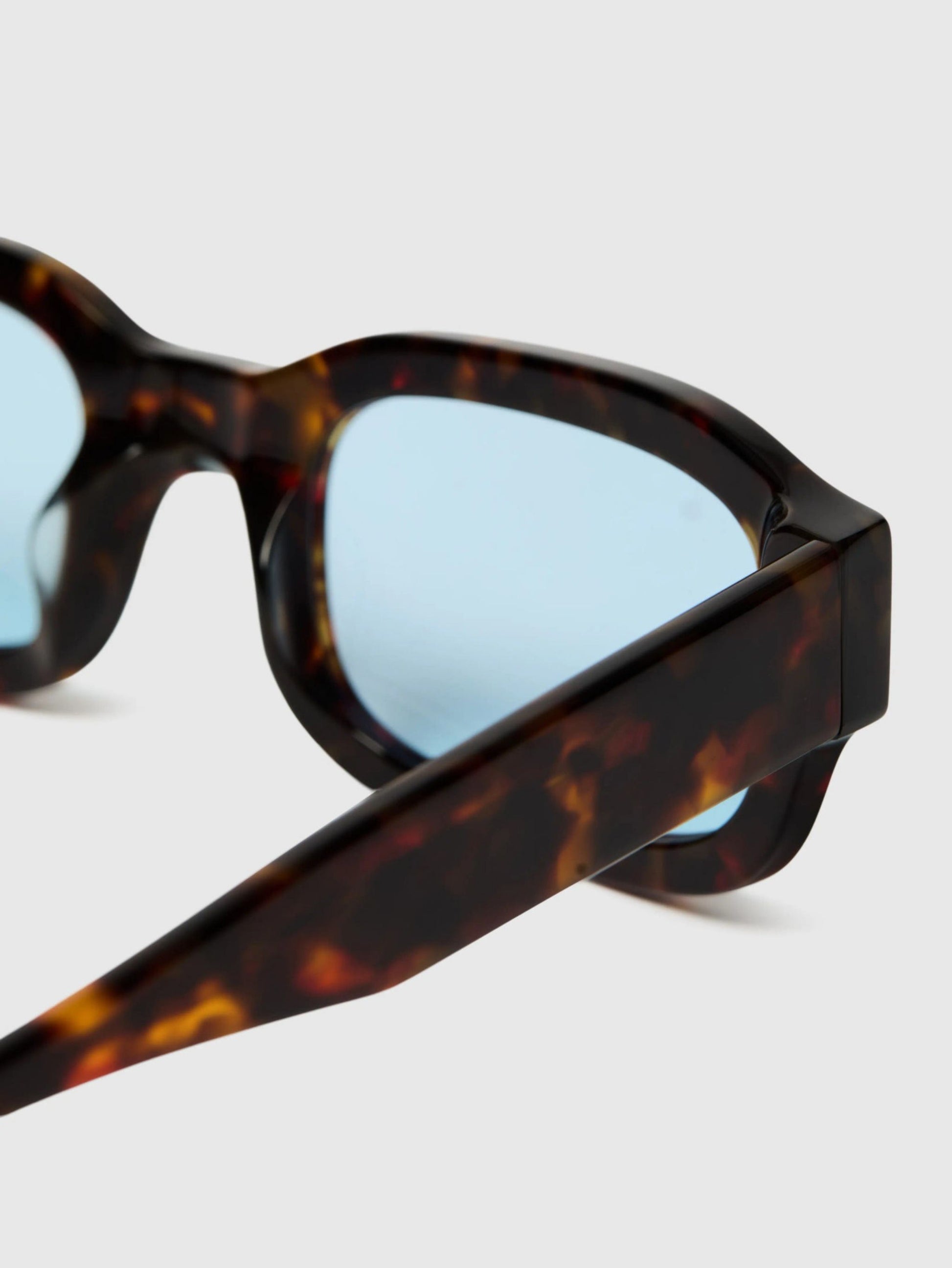 Sunglasses with tortoiseshell frame and blue lenses on a white background