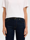 Person wearing dark blue jeans with belt and a white t-shirt on a plain background